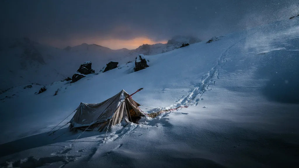 Verlassenes zerrissenes Zelt auf schneebedecktem Berghang in der Dämmerung